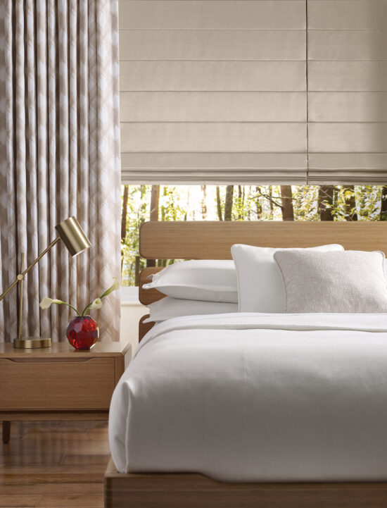 Roman shades paired with drapery panels for layered light control in a bedroom