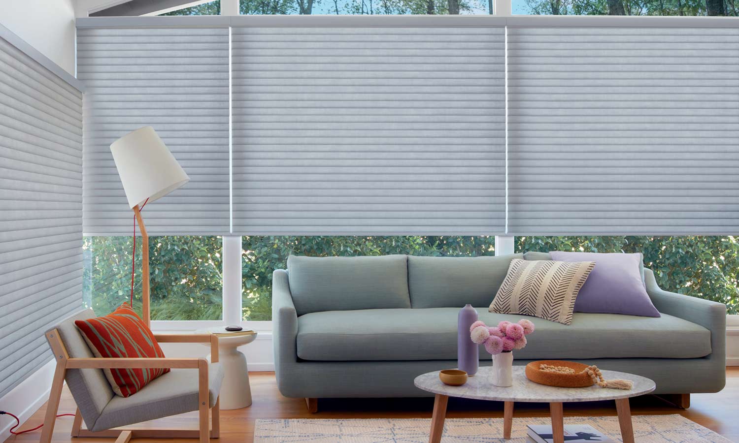 cellular roller shades on floor to ceiling windows in living room with blue furntiure