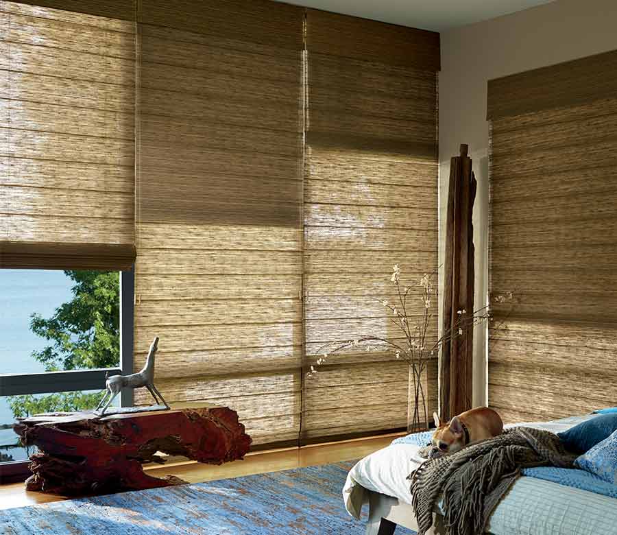 master bedroom with large floor to ceiling window treatments in caramel shades in organic materials