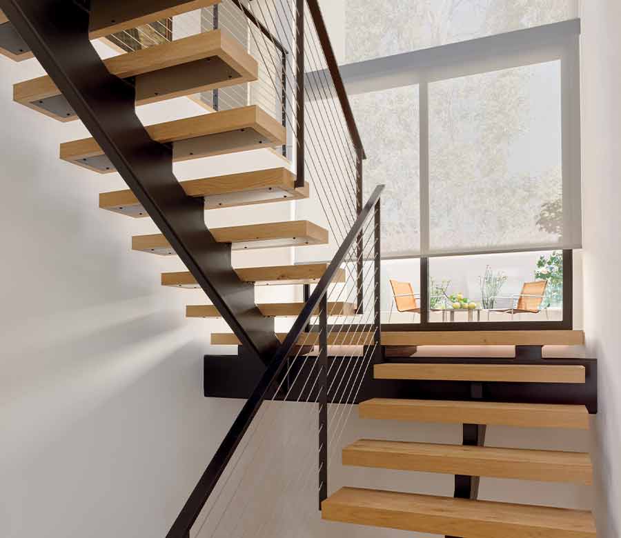 Modern floating stairs with landing overlooking backyard covered by roller shades