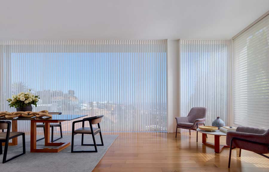 Sunny, spacious dining room that has two chairs and a side table for a conversation off to the side. There are Luminette Privacy Sheers on the windows. 