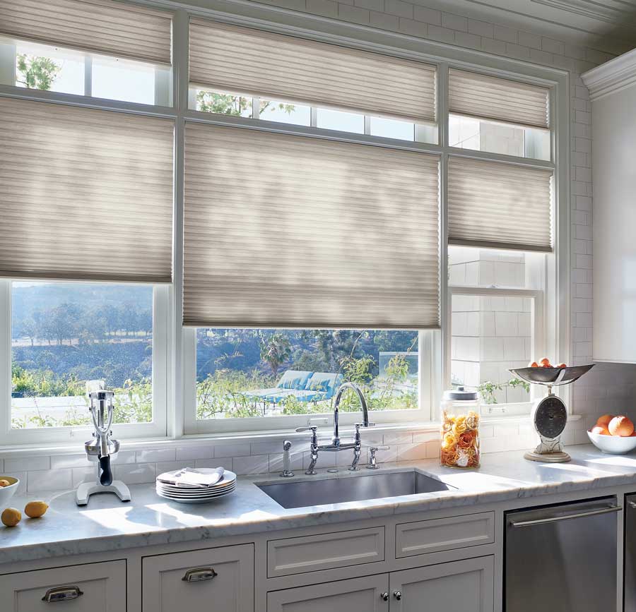 Windows with honeycomb shades above a kitchen sink