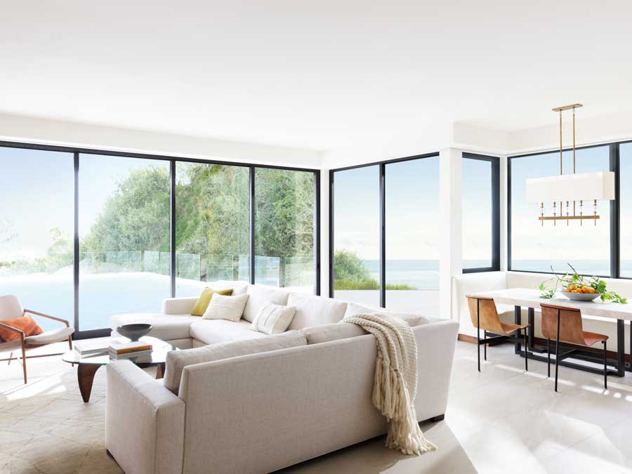 floor to ceiling black trim windows that overlook a pool from the living room 