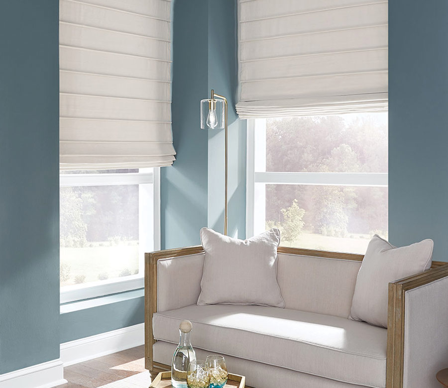 cream fabric custom window treatments in corner window blue walls and settee