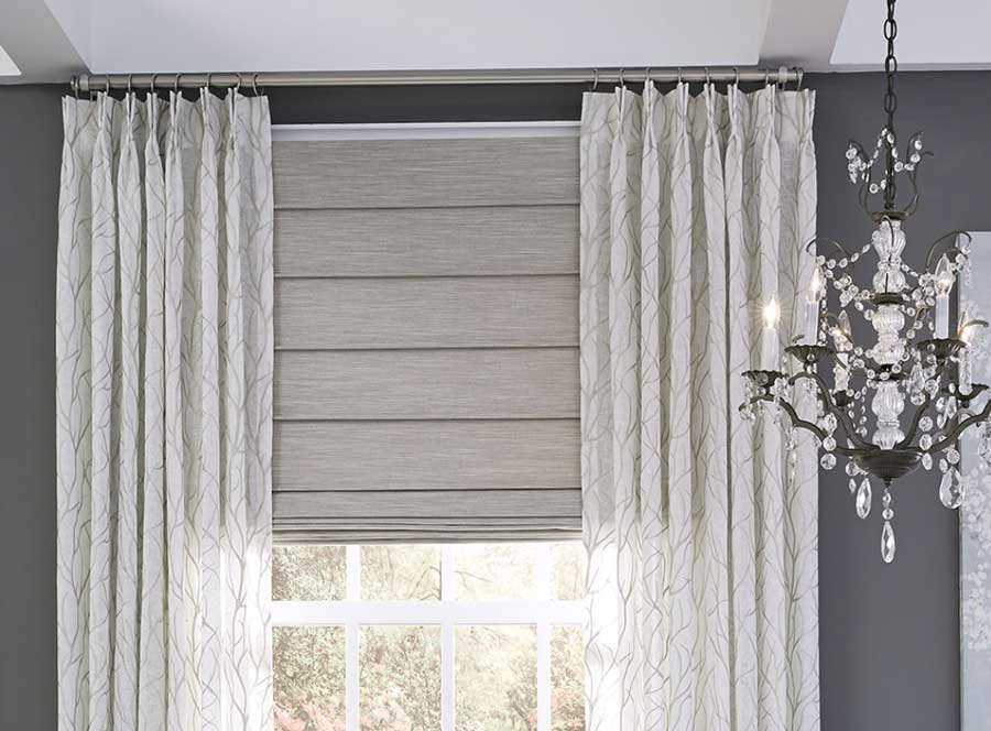 custom drapery pinch pleat header layered with gray fabric roman shade in Naples FL