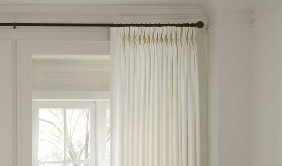 light-filtering fabric with triple pleat pinch pleat drapes on a black rod