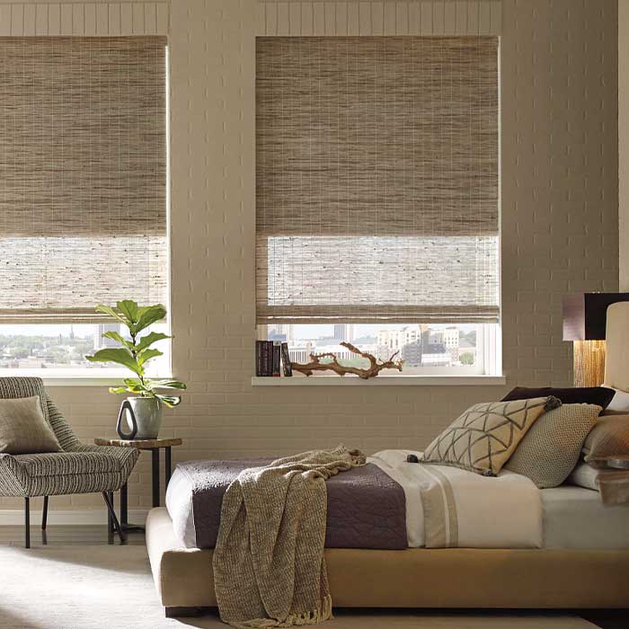 Provenance woven wood shades with a secondary cellular shade in a bedroom for room darkening and privacy